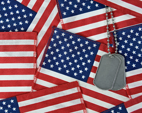 military dog tags laid over numerous american flags, memorial day flags