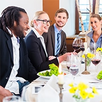 A group of business people gathered around a table having a meal
