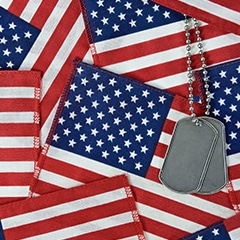 military dog tags laid over numerous american flags, memorial day flags